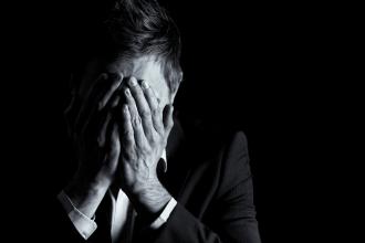
		Ein Mann ist traurig und hat sein Gesicht in die Hände gelegt
	